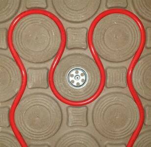 Eine elektrische Fußbodenheizung mit roten Heizrohren und einem Thermostat. Fußbodenheizung für angenehme Wärme.