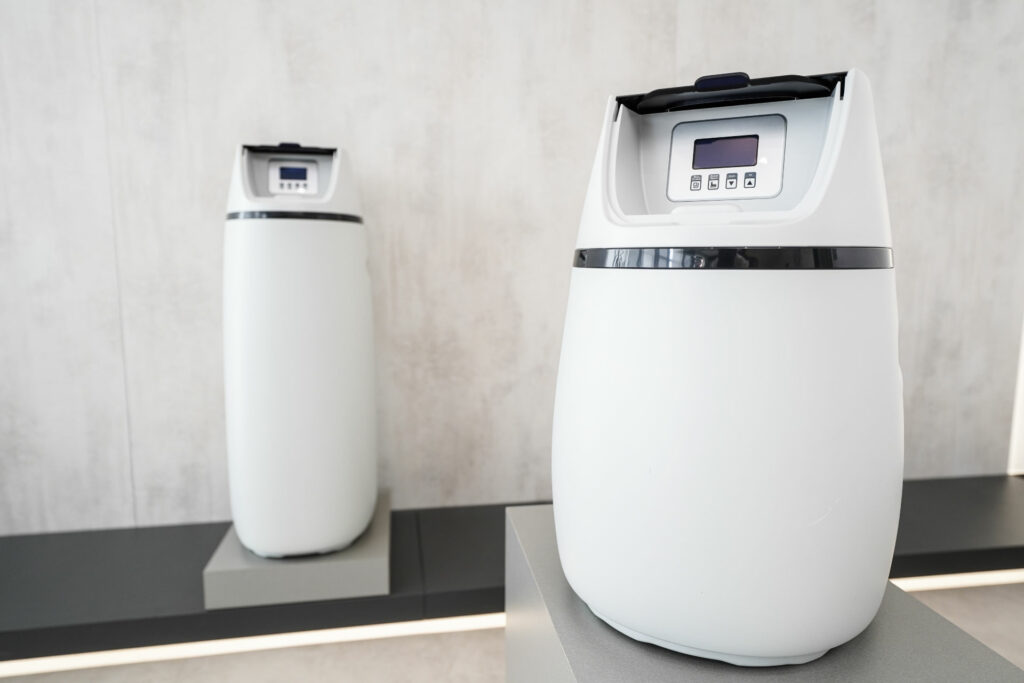 Zwei moderne, weiße Wasserfilter mit digitalem Display. Sie stehen auf einer Arbeitsplatte in einem hellen Raum.